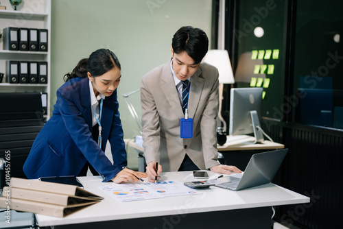 Two young Asian professionals engaged in teamwork and business discussions in office