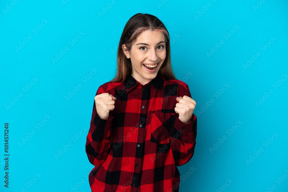 Young caucasian woman isolated on blue background celebrating a victory in winner position Young caucasian woman isolated on blue background celebrating a victory in winner position