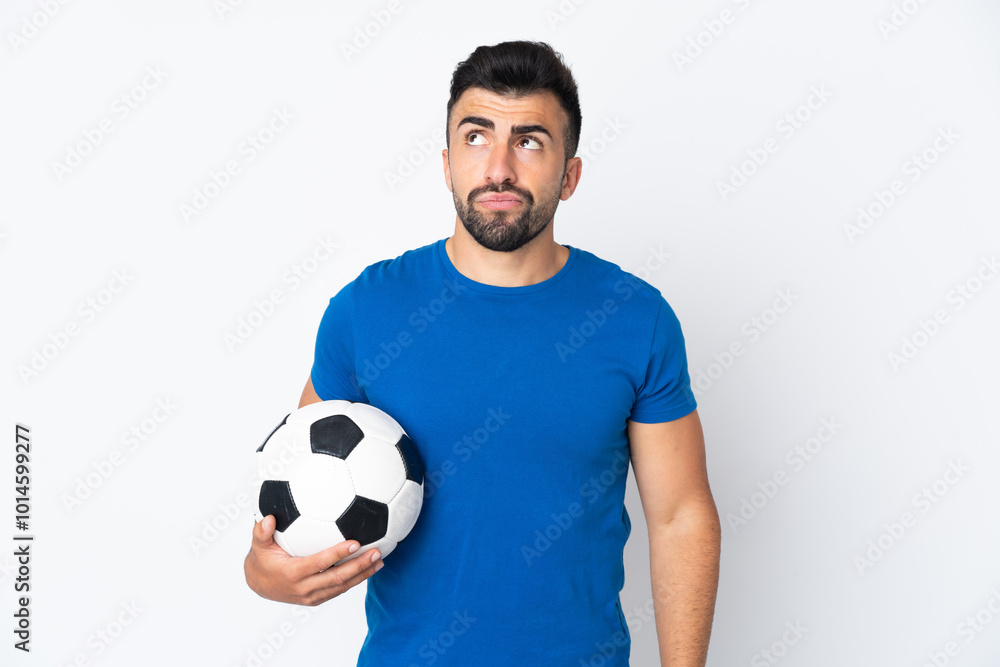 Handsome young football player man over isolated wall and looking up Handsome young football player man over isolated wall and looking up