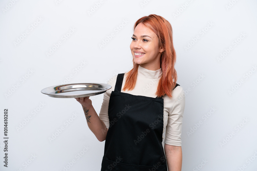 Young Russian waiter with tray isolated on white background looking side Young Russian waiter with tray isolated on white background looking side