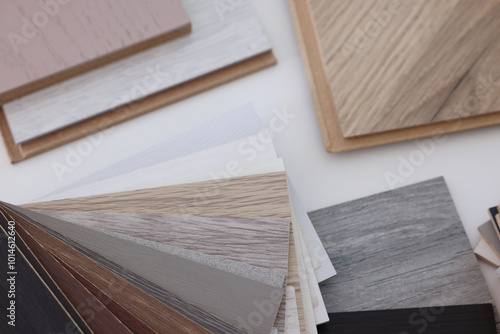 Different samples of wooden flooring on white table, above view