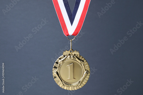 Golden medal with striped ribbon on grey background