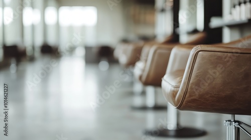 A neat line of plush leather chairs is arranged in an immaculate and minimalist salon, emphasizing modern design and elegance amidst ample open space and natural light.