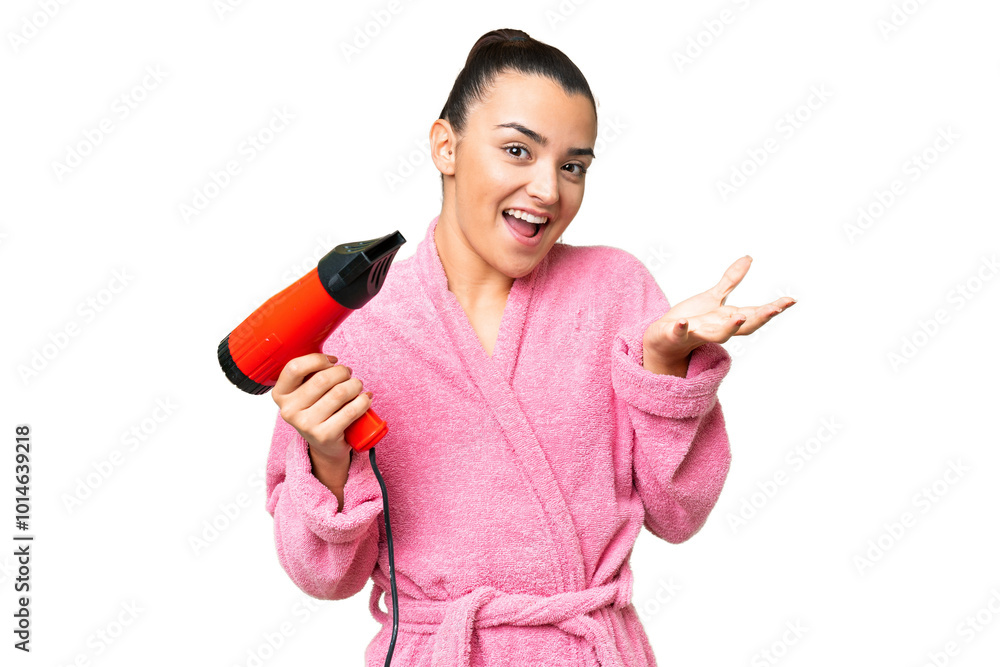 Young woman in a bathrobe holding a hairdryer over isolated chroma key background with shocked facial expression Young woman in a bathrobe holding a hairdryer over isolated chroma key background with shocked facial expression