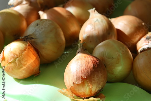 Fresh onions piled high on a green cutting board, ready for use in cooking.