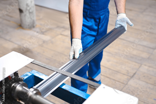 Professional engineer man in blue uniform works in factory. Rolled metal, metal processing and manufacturing of metal fence