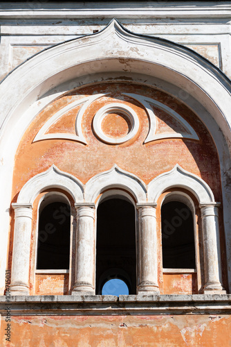 This image features an old Orthodox church with domes and a neoclassical design, including large columns and faded walls. The structure shows signs of wear, set against a bright sky and autumn trees. photo