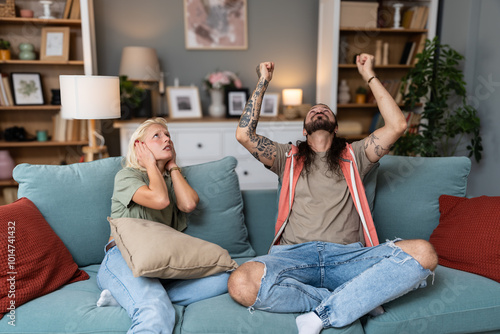 Young couple stares at the ceiling and yells because a neighbor upstairs is having a party with loud music or renovating an apartment and workers are drilling with heavy tools. Noise pollution concept