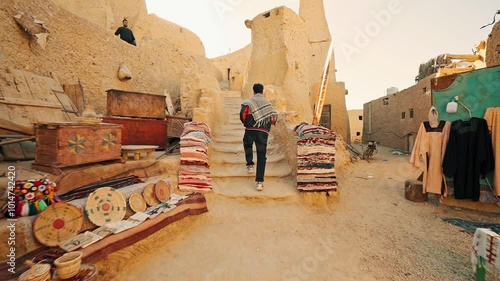 a young man traveler walking alone exploring shali castle in siwa oasis in egypt at sunset, siwa oasis, Egypt.