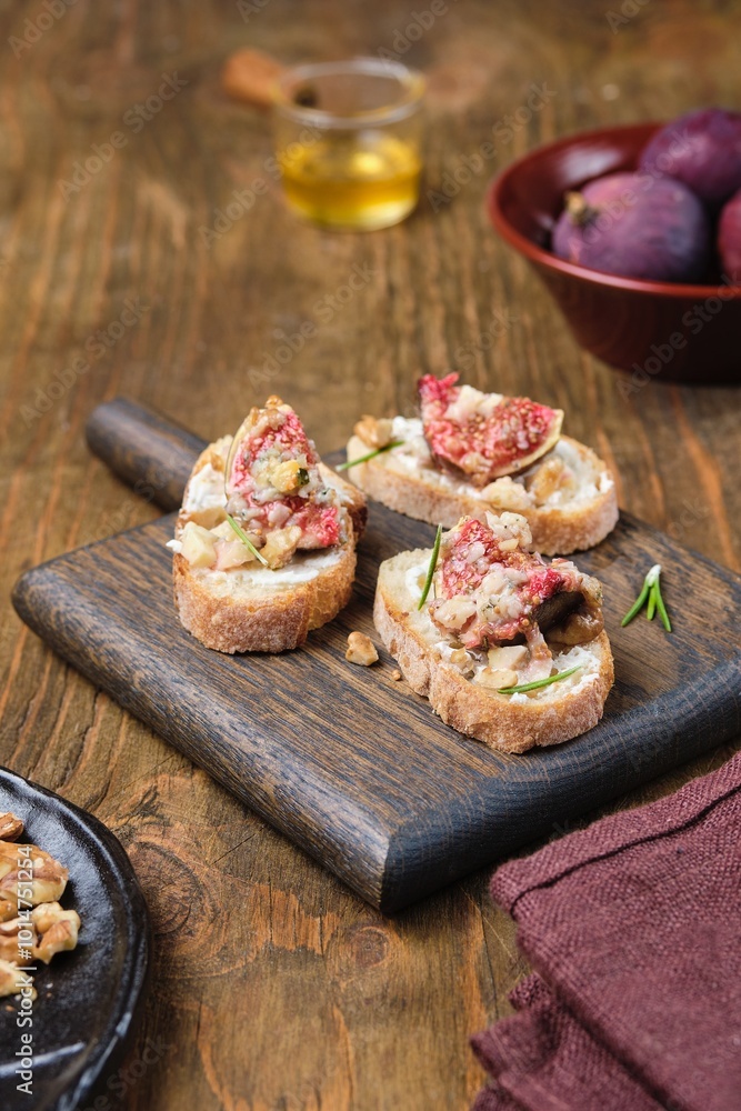 Bruschetta, open sandwich with baked figs, blue cheese and walnuts on a wooden board. Recipes figs. Bruschetta, open sandwich with baked figs, blue cheese and walnuts on a wooden board. Recipes figs.