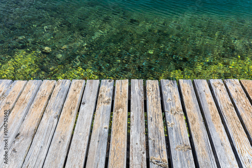 Wooden board empty over sea, can be used for display or present a product. Summer season. Empty perspective wooden planks over the reflection of green water, product display template.