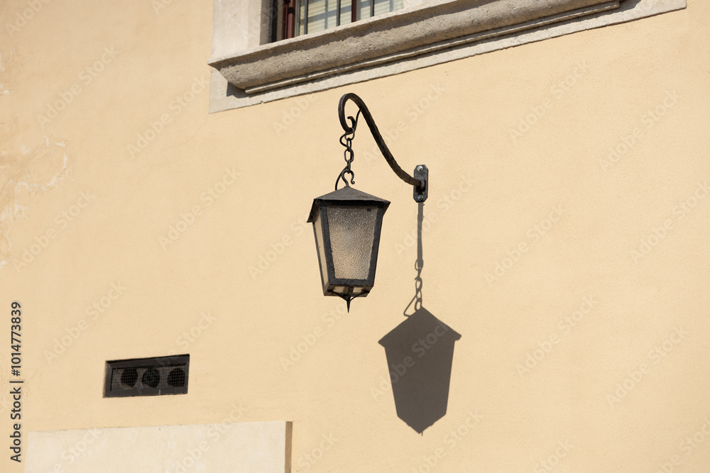 Old antique metal lamp at the old wall. Victorian vintage street lantern at the day time, turned off. The wall lamp on the old street