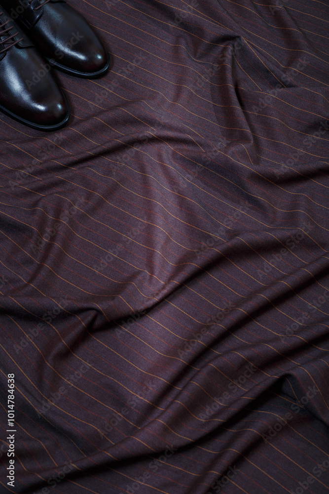 Obraz premium Male classic formal brown leather shoes on brown fabric suit background. Only toes visible. Copy space for logo design, advertising. Natural leather accessories for men