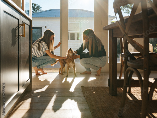 Mother and daughter petting their dog in the kitchen. photo