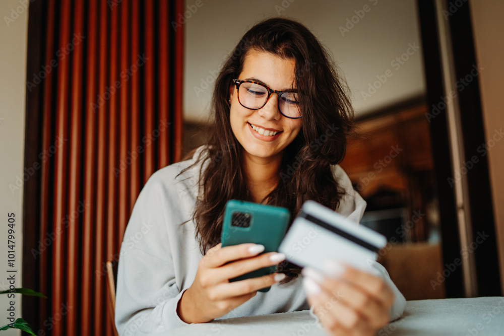Fototapeta premium Young caucasian woman shopping online on smartphone using credit card 