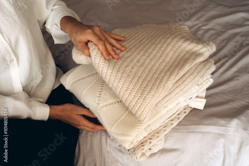 A Woman Organizing Cozy Knitwear and Neutral Clothing