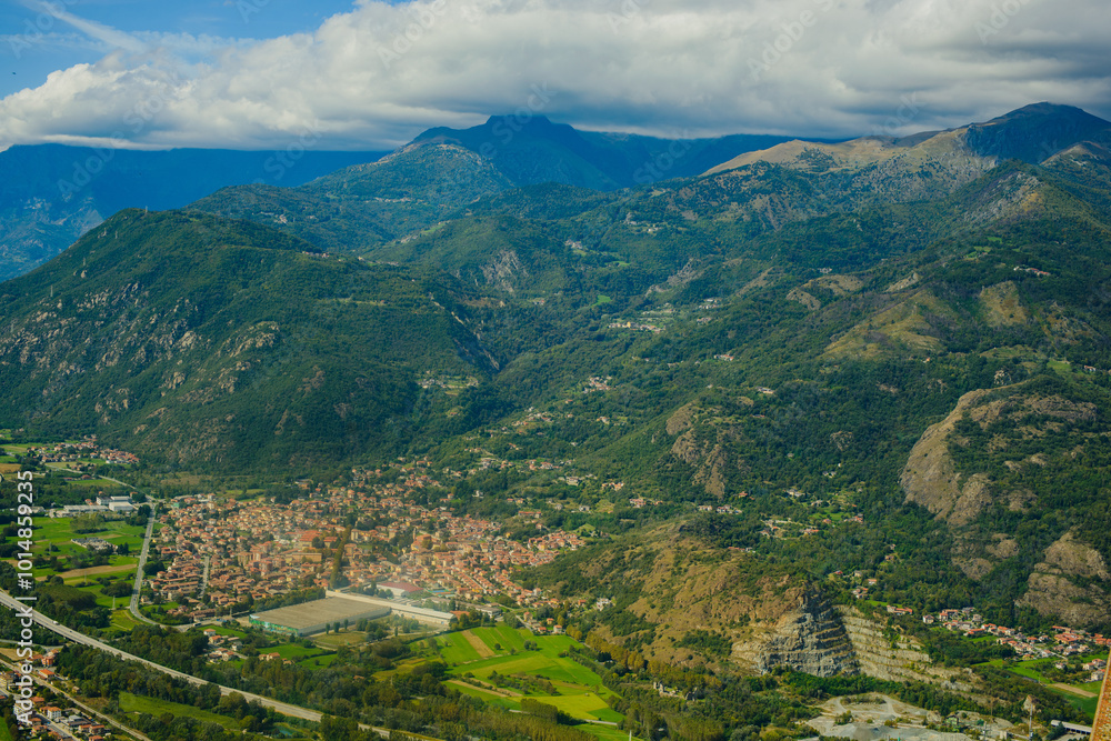 Obraz premium Panoramic landscape of the Italian city, photos from a drone, quadcopter, aerial photography. The city, the houses with tiled roofs, the road and the mountains. Layout. A miniature. View of Piedmont, 