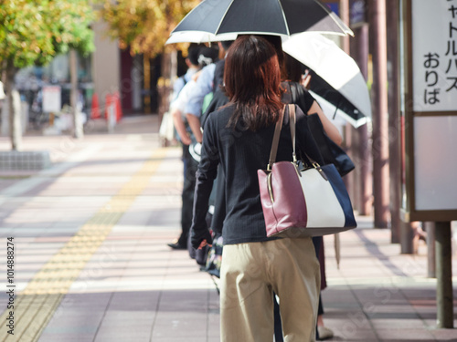 夏の朝の通勤時間でバス停の長い待ち列の様子