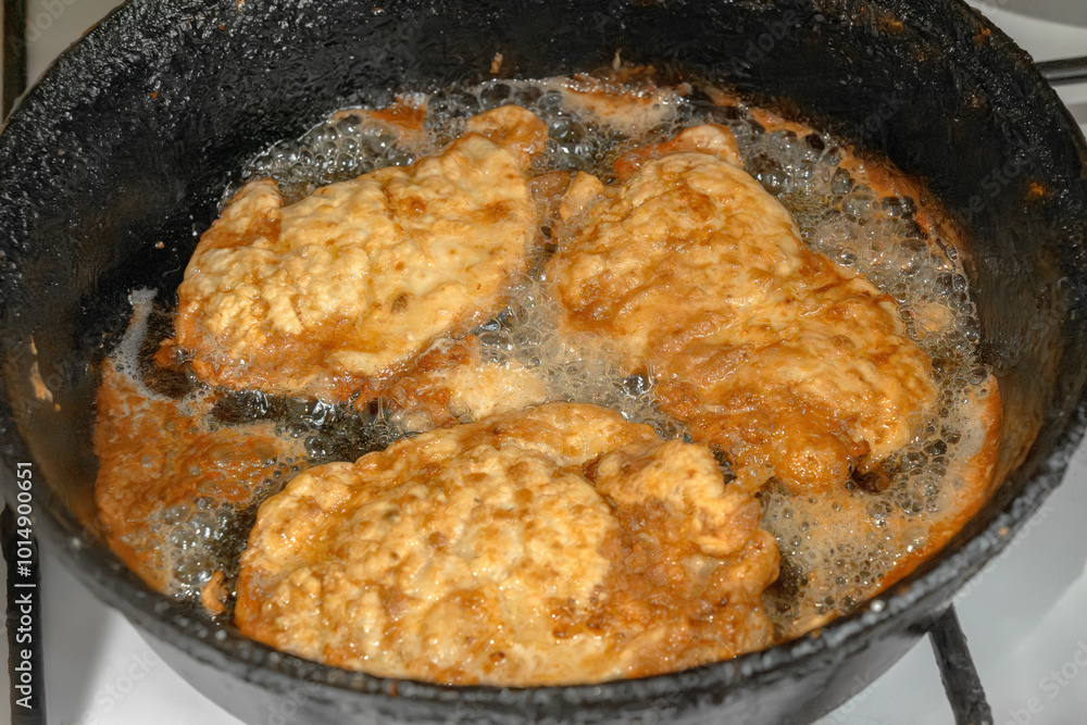 Schnitzel or chops are fried in boiling oil on an old cast iron hot frying pan. Close-up Schnitzel or chops are fried in boiling oil on an old cast iron hot frying pan. Close-up