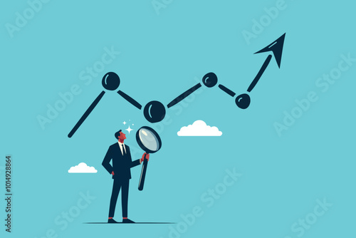a businessman stands with a magnifying glass observing the rising graph growth