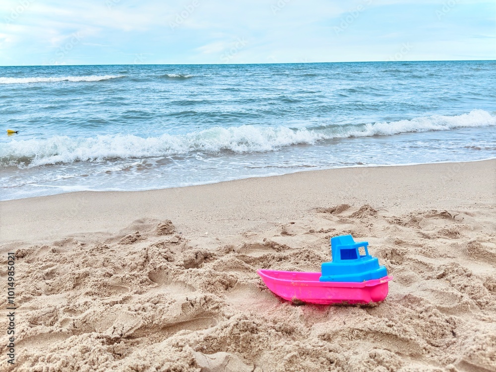 Beach Toys in the Sand. Set of plastic sand toys for children On sand near sea. sand beach with accessories. Boat toys on sand Beach Toys in the Sand. Set of plastic sand toys for children On sand near sea. sand beach with accessories. Boat toys on sand