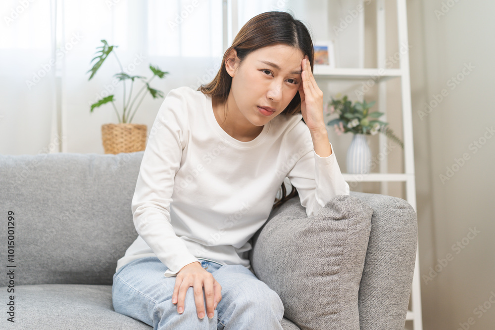 Dizzy asian young woman, girl headache or migraine pain suffering from vertigo while sitting on couch in living room at home, holding head with hand, health problem of brain or inner ear not balance. Dizzy asian young woman, girl headache or migraine pain suffering from vertigo while sitting on couch in living room at home, holding head with hand, health problem of brain or inner ear not balance.