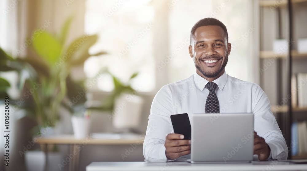 Smiling businessman holding smartphone and working on laptop in modern office environment. Smiling businessman holding smartphone and working on laptop in modern office environment.