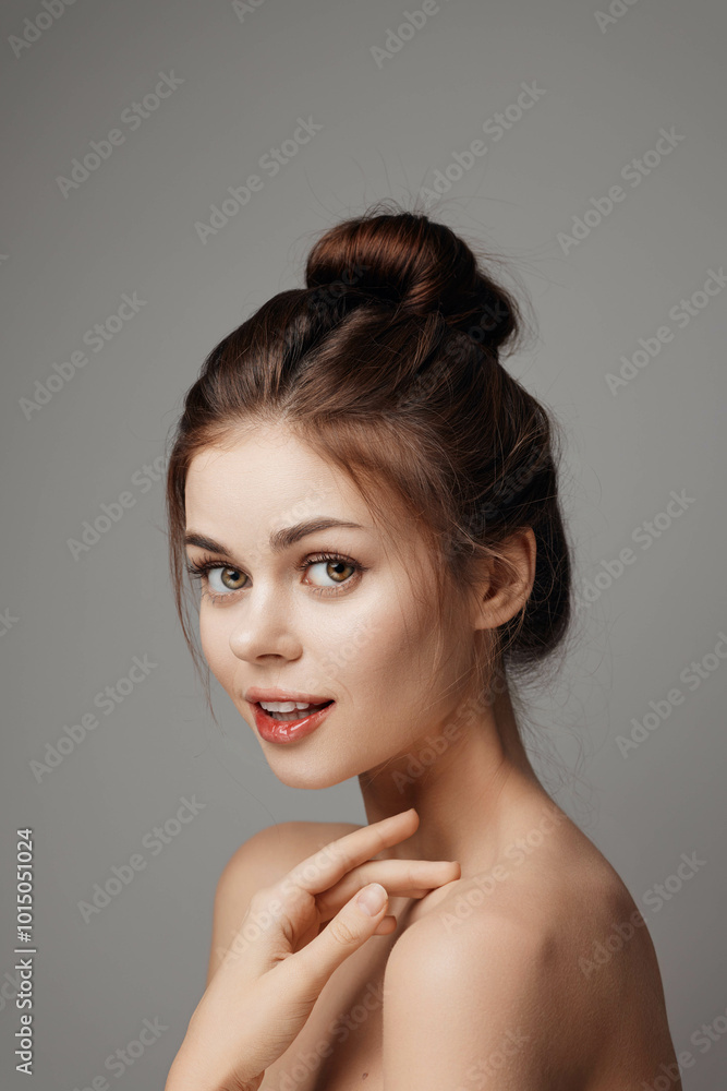 Beautiful young woman with hands on face posing on gray background Beautiful young woman with hands on face posing on gray background