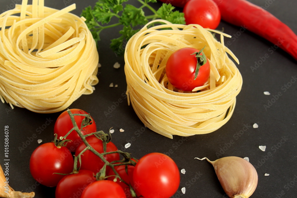 On a black background lie vegetables with pasta nests. On a black background lie vegetables with pasta nests.
