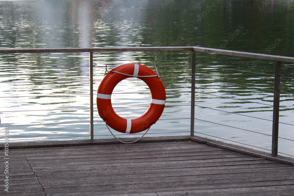 Fototapeta premium There is a lifebuoy hanging on the fence at the pier near the reservoir.