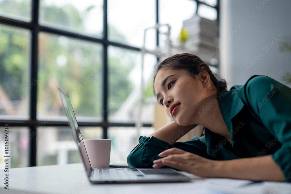 A woman is sitting at a desk with a laptop and a cup of coffee A woman is sitting at a desk with a laptop and a cup of coffee