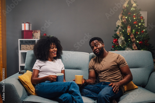 Diverse couple enjoying relaxed coffee time by the Christmas decor