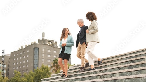 Fotografie Smiling business colleagues discussing while walking downstairs