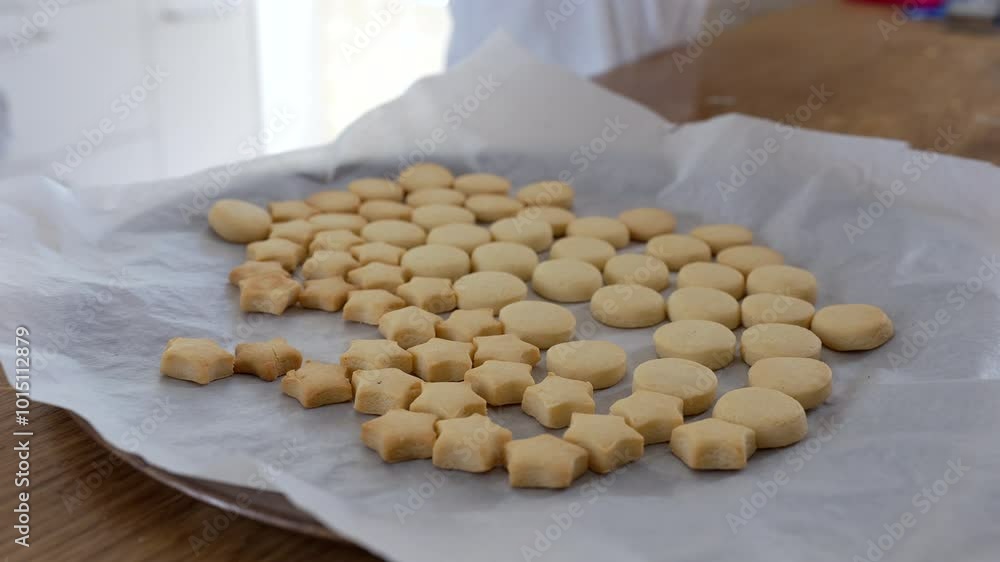 Freshly baked star and round-shaped cookies cooling on parchment paper in the kitchen. the simple joy of homemade baking and creative food preparation Freshly baked star and round-shaped cookies cooling on parchment paper in the kitchen. the simple joy of homemade baking and creative food preparation