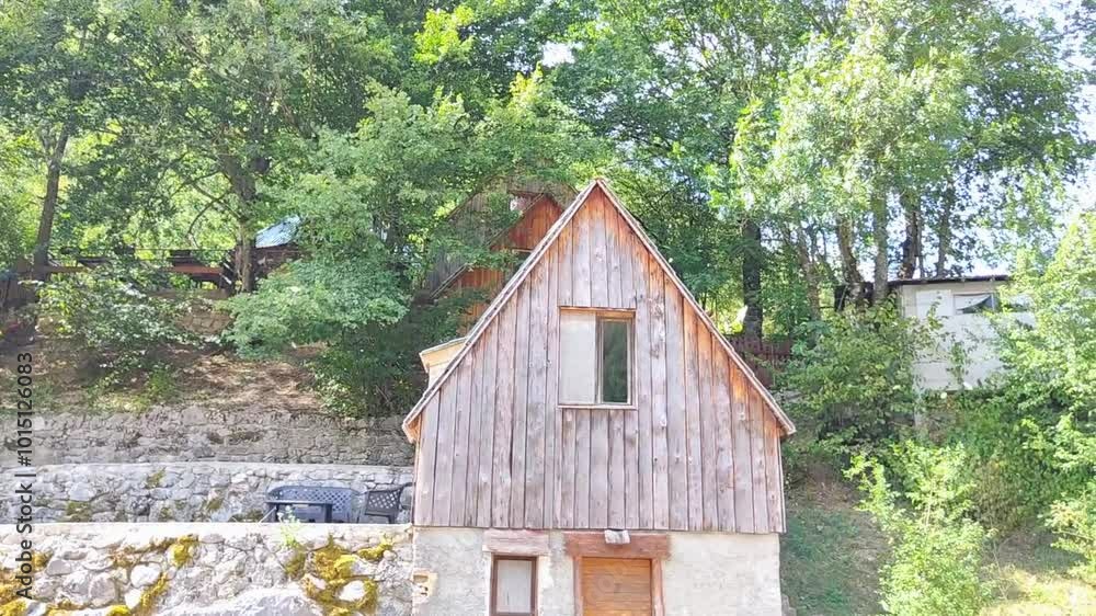 Summer in the mountains. The summer wind tears the leaves off the trees and scatters them in different directions. House in a village. Summer in the mountains. The summer wind tears the leaves off the trees and scatters them in different directions. House in a village.
