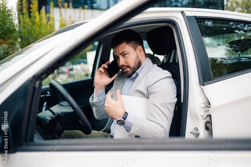 Businessman having an important phone call while sitting in his car