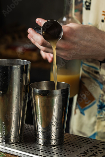 Bartender pouring liquid from a jigger into a shaker photo