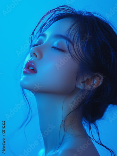 A serene moment captured of a young Korean woman bathed in soft blue light, highlighting her graceful profile against a tranquil backdrop