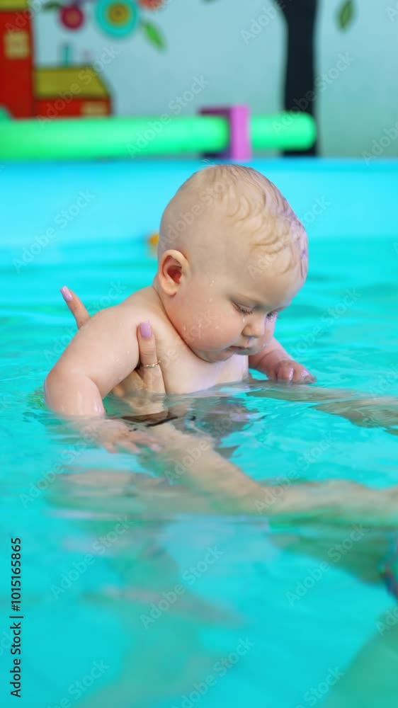 Trainer holds a baby in the swimming pool on the straight hands. Coach deeps a child's face into water learning him to swim. Vertical video. Trainer holds a baby in the swimming pool on the straight hands. Coach deeps a child's face into water learning him to swim. Vertical video.