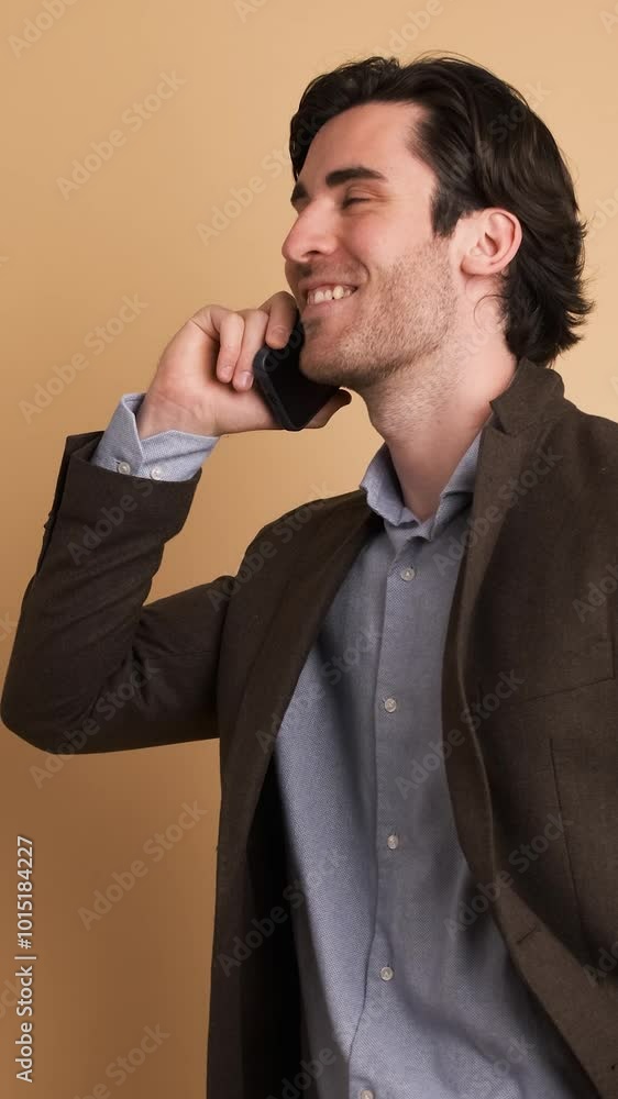Smiling adult businessman talking on smartphone in brown studio Smiling adult businessman talking on smartphone in brown studio