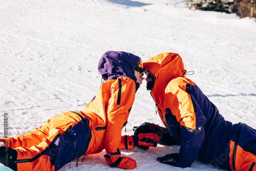 A guy and a girl in ski suits in the snow. Snowboarders on the top of the mountain photo