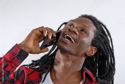 Cheerful African Rastafarian man using a cell phone