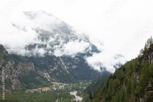 Passing clouds over idyllic landscape in the Alps with snow-capped mountain tops in the background.