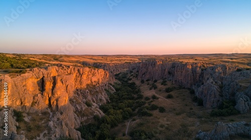 Jagged rock formations rise dramatically against a vibrant blue sky, with deep shadows enhancing the textures of the rugged terrain during sunset