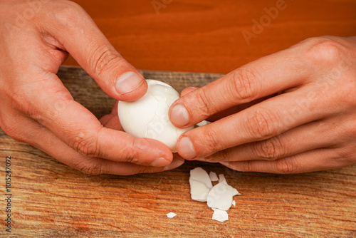 Man holding chicken egg over wooden board. Boiled egg. Cleaning egg from shelling, close up. Healthy food. Protein. Sportsmen's food. Preparing food. Horizontal photo. Vegetarian.