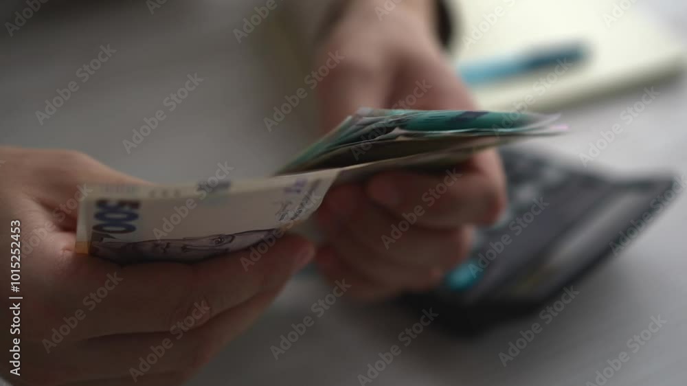 Close-up of a man calculating monthly income and results using a calculator, checking electronic bills in an e-banking computer application, managing expenses and household cash payments
