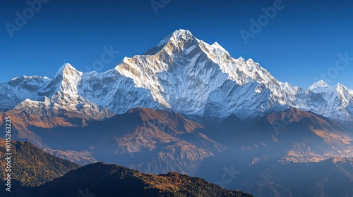 Majestic snow-capped mountain peak rises above a range of forested hills, bathed in the golden light of sunrise.