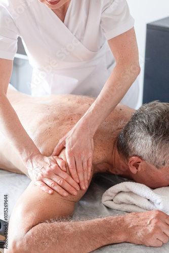 Man receiving back massage from masseur in spa