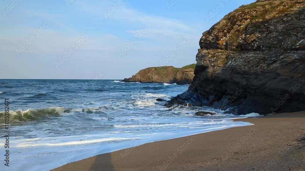 Waves rolling onto the sandy shore with a view of cliffs Waves rolling onto the sandy shore with a view of cliffs
