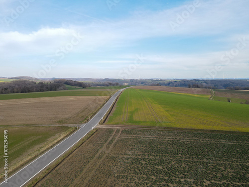 View from above of a landscape with farm fields and a long road in spring